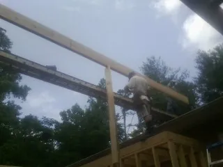Carpenter setting a ridge beam over a new addition frame — Ice Dam Removal by Roofing Brothers in Spring Arbor
