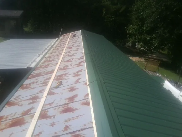Old rusted panels beside newly installed green metal roofing — Wind Damage Roof Repair by Roofing Brothers in Spring Arbor