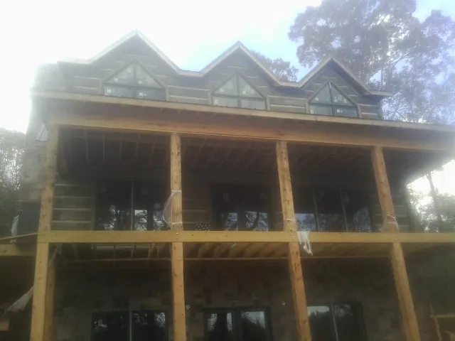 Dormers and porch framing on a large log home under construction — Roof Coating work by our crew in Spring Arbor