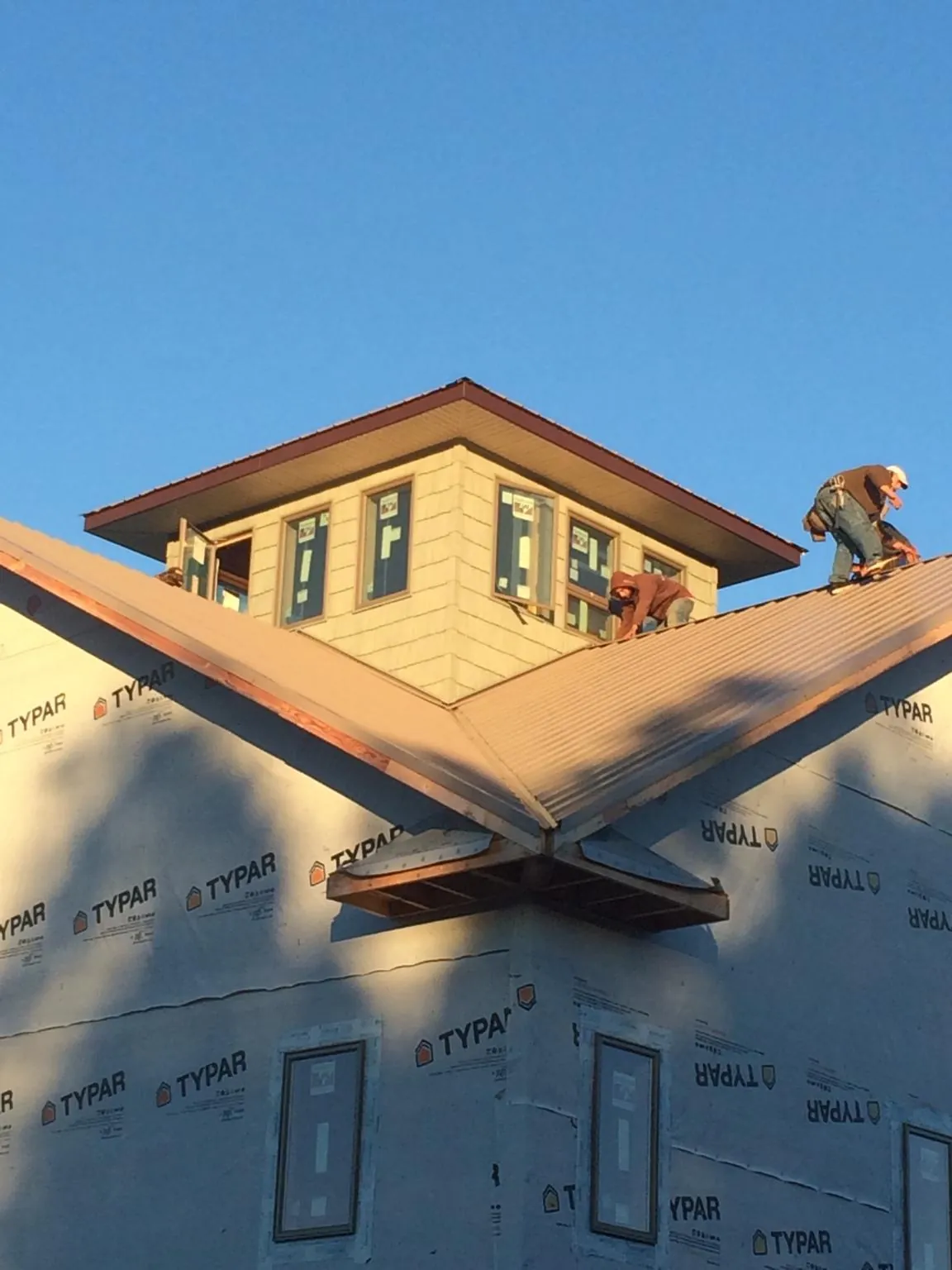 Roofers working around a rooftop cupola on a new metal roof at sunset — Roof Waterproofing in Spring Arbor by Roofing Brothers